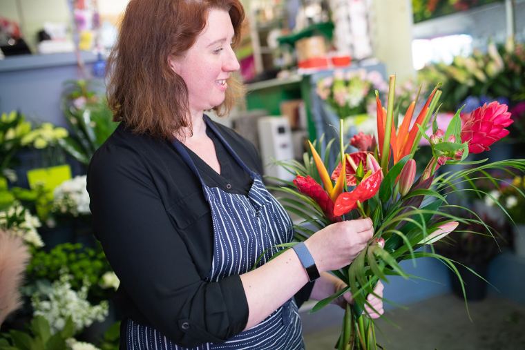 A florist tying a bouquet of tropical flowers